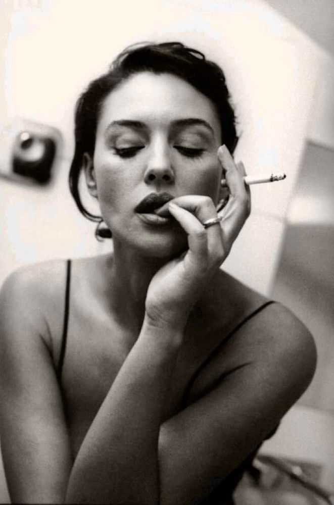 Monochrome photo of Monica Bellucci holding a lit cigarette 