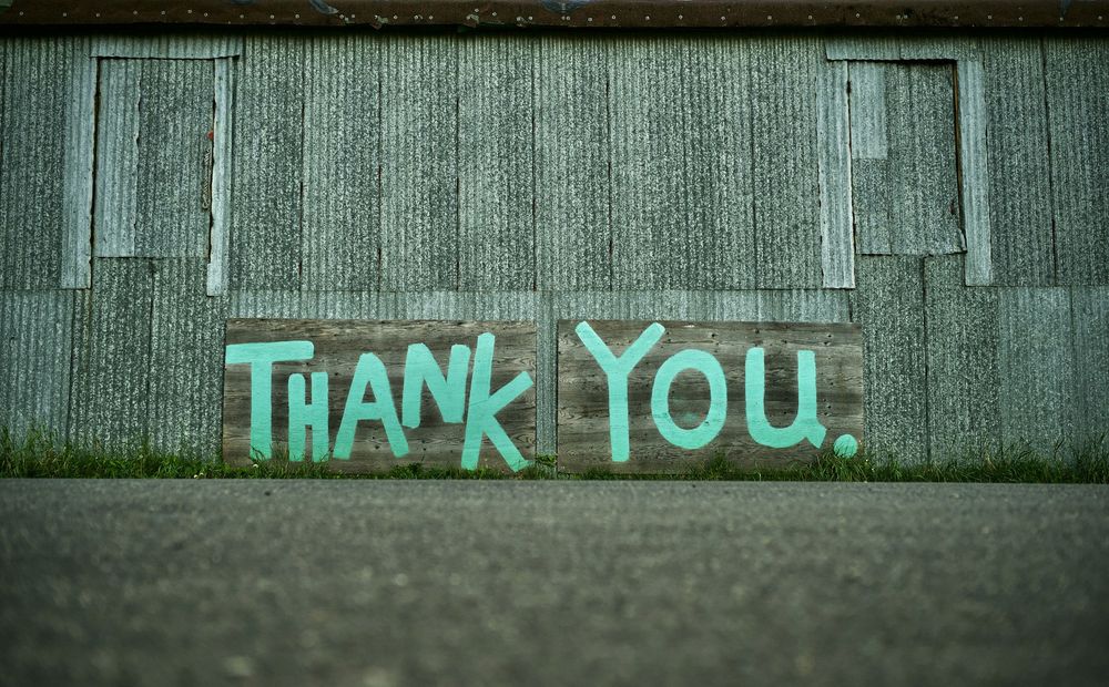 Metal sided building with Thank You painted on the side in blue paint.