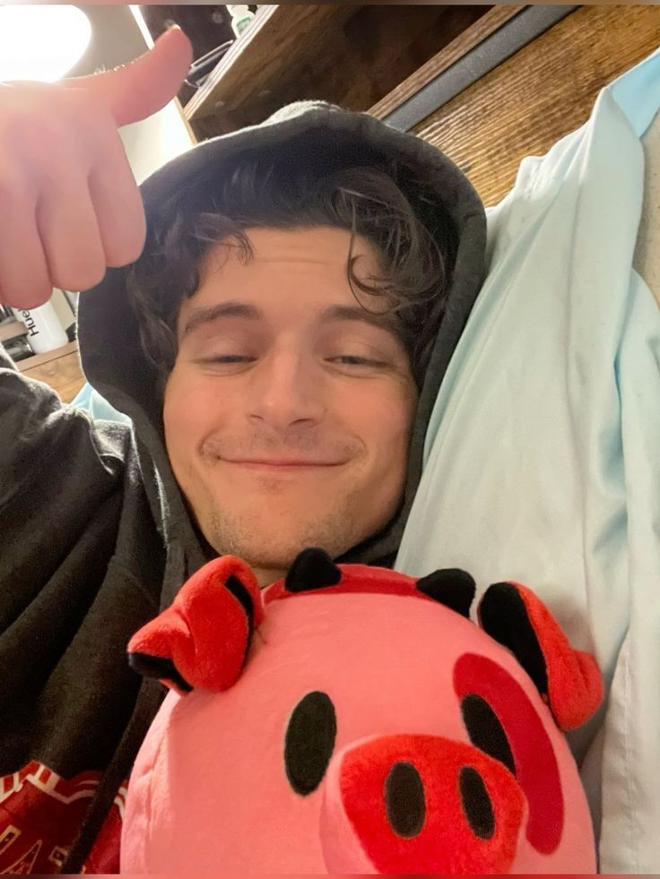 Foto de referencia: Blake Roman sonriendo con un peluche de Fat Nuggets, un cerdito en la serie Hazbin Hotel.