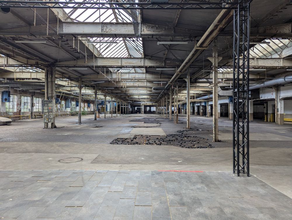 Eine alte verlassene Industriehalle mit Eisenträgern an der Decke. Die Halle ist leer und verkommt an einigen Stellen.