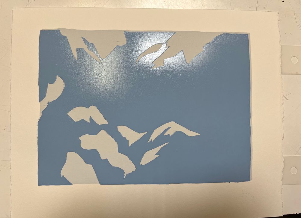 A photo of a piece of paper with flat light blue and gray shapes. Taken in bad lighting (sorry ^^;;)