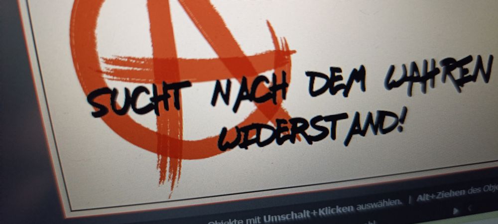 Ausschnitt eines abfotografierten Monitors. Es steht in schwarzen Großbuchstaben "sucht nach dem wahren Widerstand" drauf, dahinter ein angeschnittenes Anarchie Symbol in rot