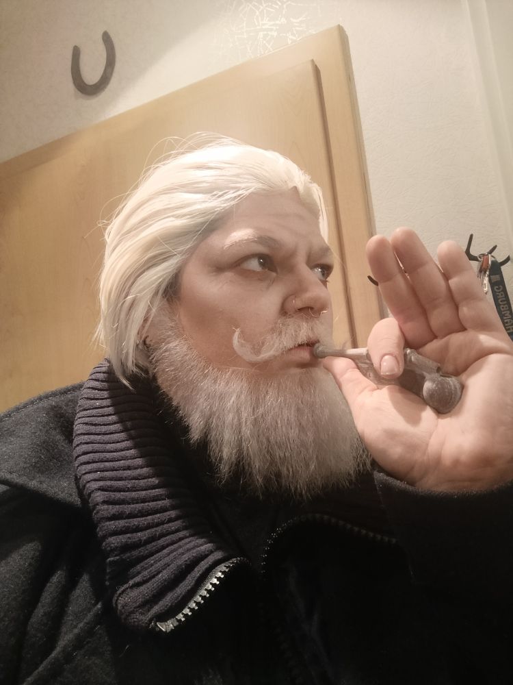 Selfie von mir im Cosplay.
Ich habe eine weiß-blonde Perücke und passenden weiß-blonden Vollbart dazu angeklebt. ich habe eine 3D gedruckte Bootsmannpfeife in der Hand und tue so, als würde ich rein pusten.