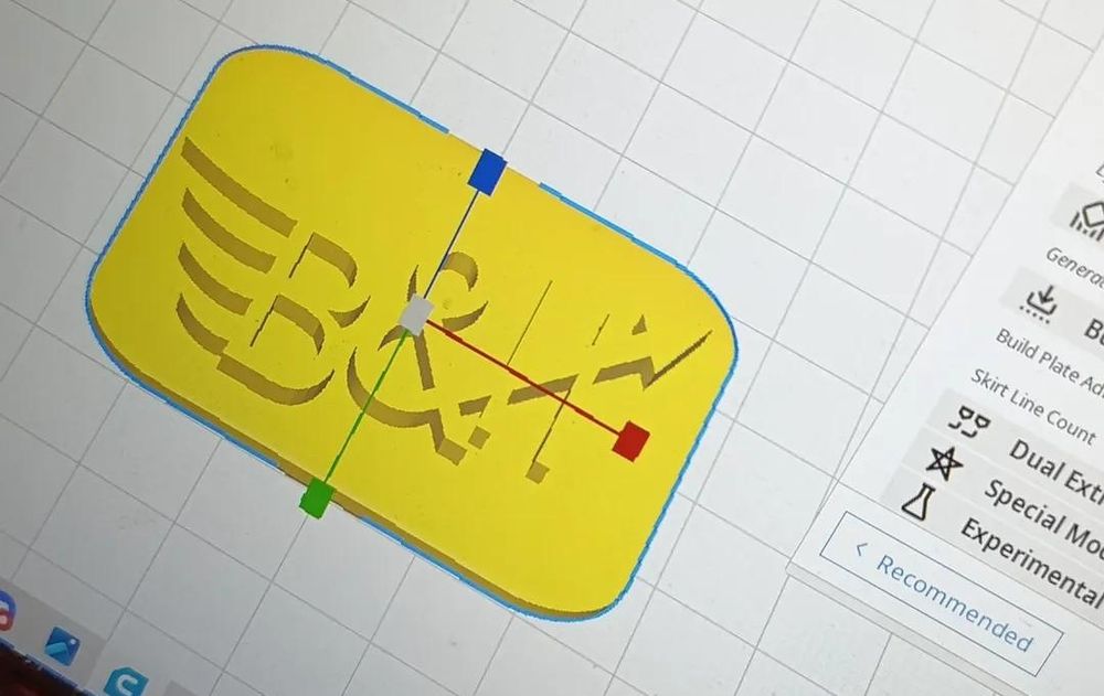 Foto eines Displays mit einem 3D Modell einer kleinen Plakette mit "B&H" drauf 