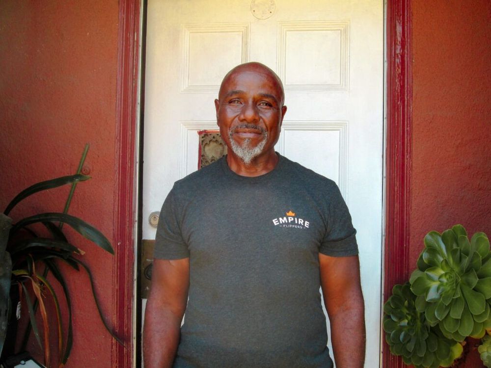 A man stands for a portrait outside his front door.