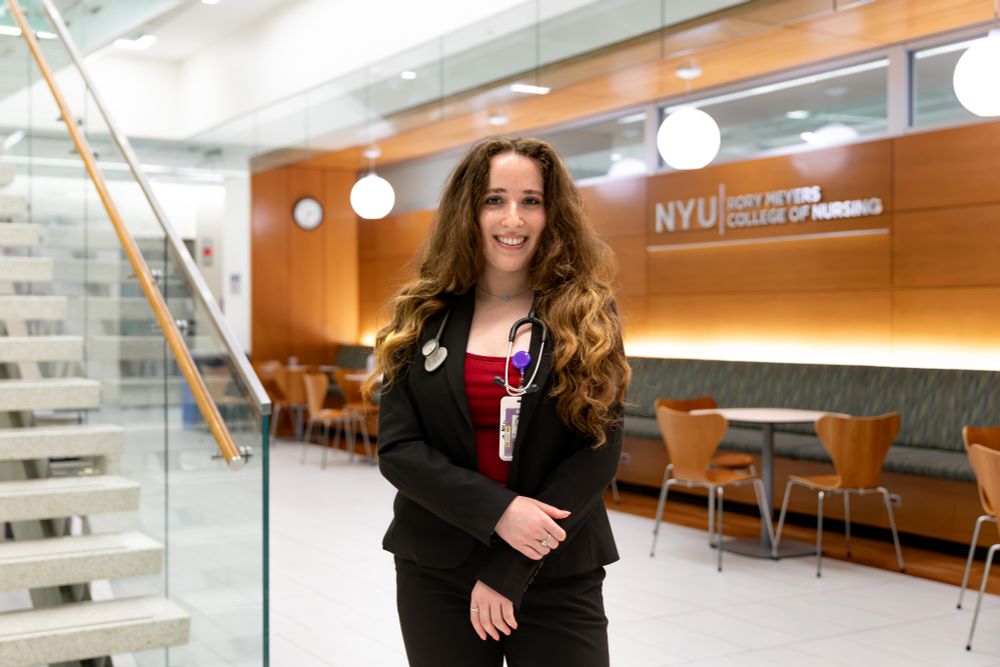 Veronica standing in front of a NYU Meyers sign in a cafeteria at a medical facility