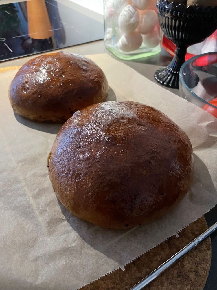 Kaksi pyöreää joululimppua jäähtymässä leivinpaperin päällä.