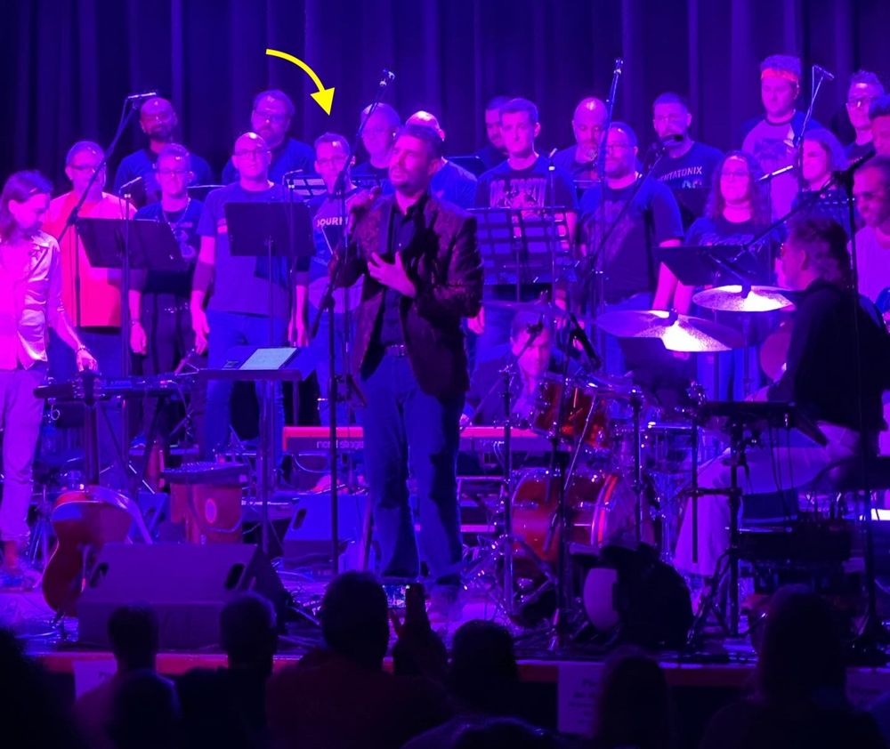 Yacht Rock Schooner and Members of the Atlanta Gay Men’s Chorus perform “The Best Damn Queen Show Ever” at Variety Playhouse in 2024. The stage is illuminated with blue and purple lights, and the chorus is behind the band.