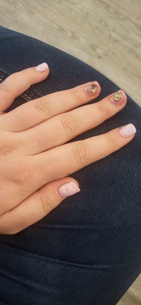 My left hand at rest, camera pointing down onto the back of my hand. My nails are decorated with sparkles and gold Sailor Moon themed charms.