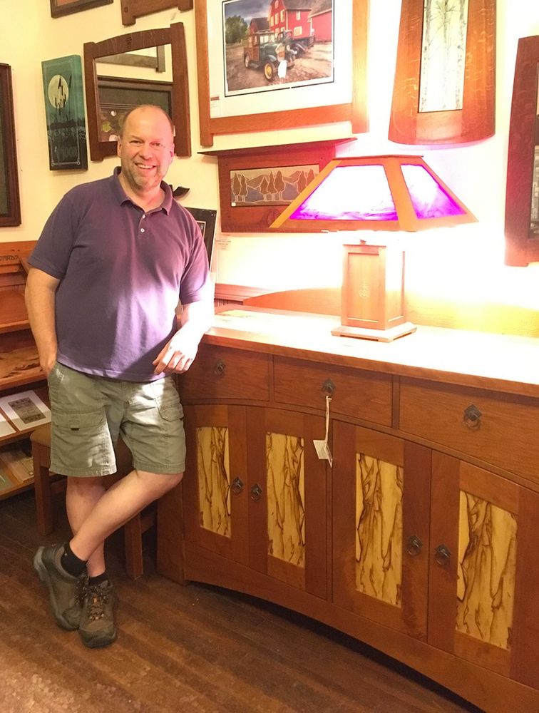 A man standing next to wooden furniture