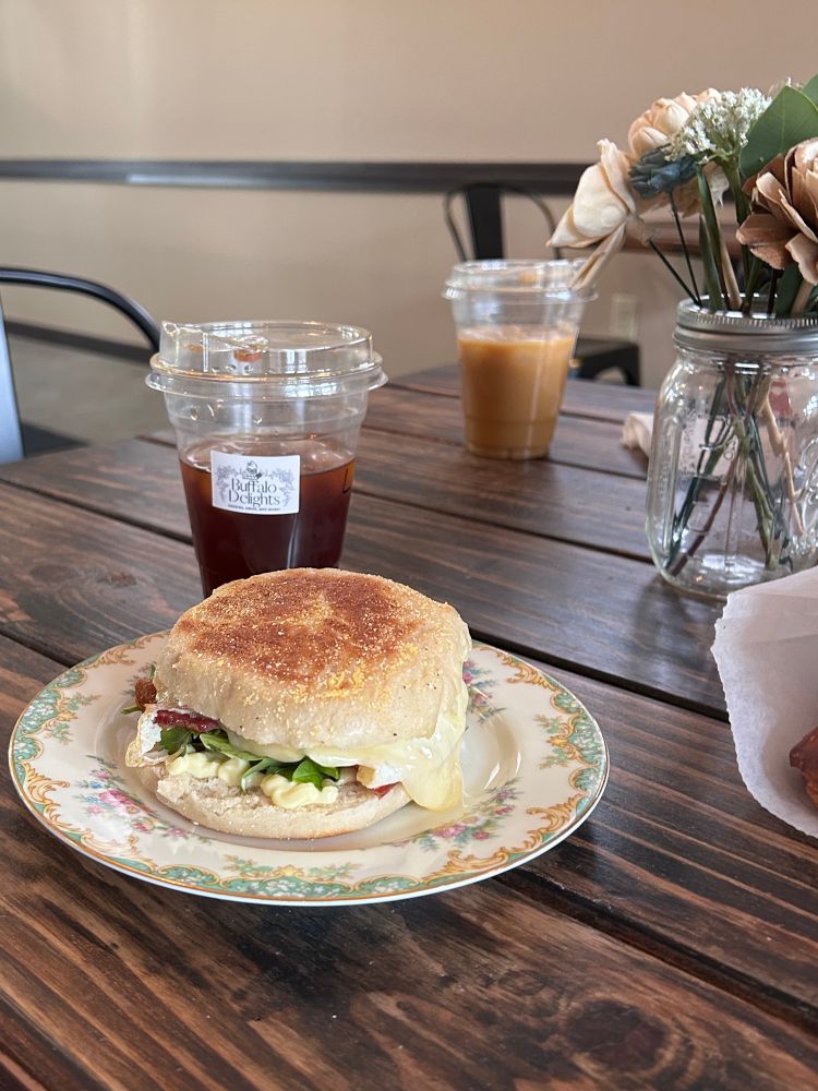 A breakfast sandwich on an English muffin and container of cold brew coffee. 