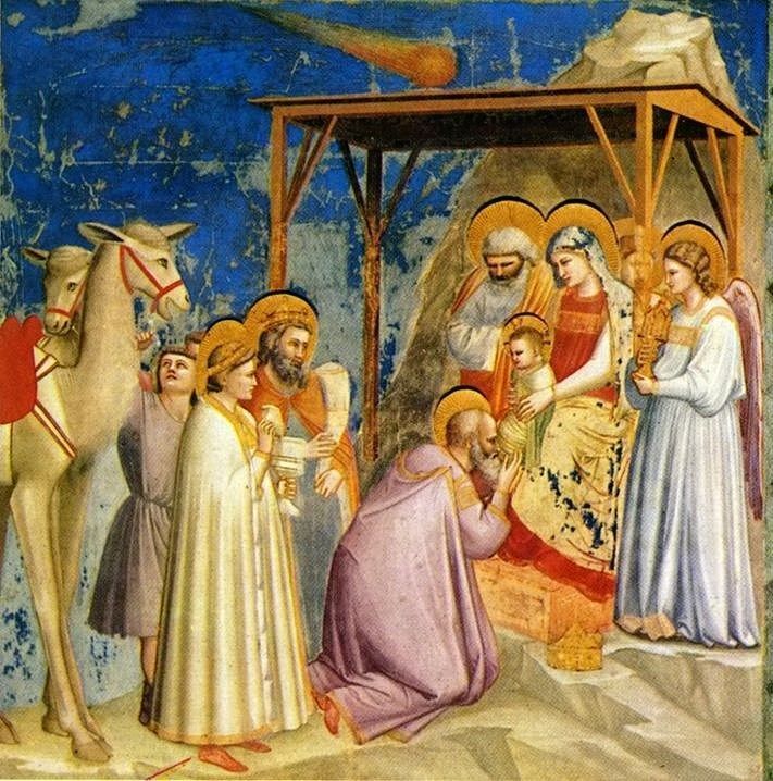 Fresque de Giotto représentant l'Adoration des Mages, où un homme agenouillé baise la main d'un enfant tenu par une femme assise, sous un abri en bois. D'autres personnages se tiennent autour d'eux, et un chameau se trouve à gauche. Un objet céleste lumineux avec une traînée est visible dans le ciel bleu en haut.