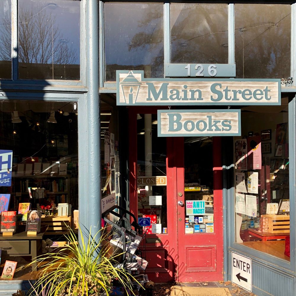 Main Street Books front entrance with large windows and red front doors. The sign says closed because I was waiting for the store to open!
