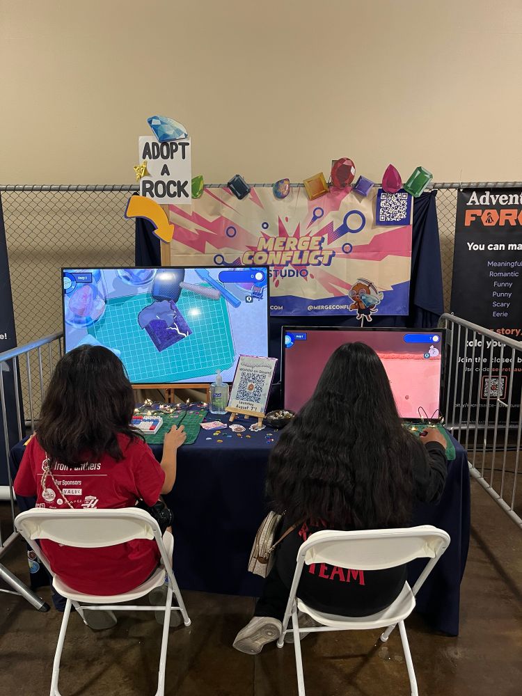 Two people sitting at the Gemporium booth at Open Sauce Live 