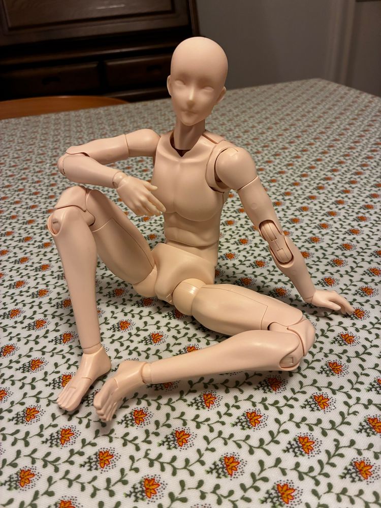 机の上にドールの素体がある写真。片膝を立てて座るポーズ。