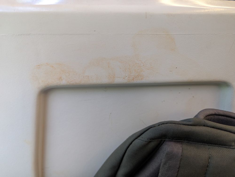 Back of a train seat. Cream with a browny/red stain smeared across it