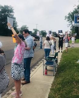 Many activists holding up their signs of protest toward passing vehicles. 