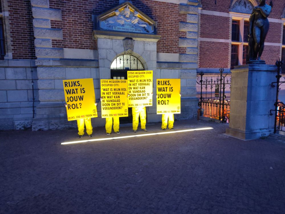 Menaen in gele pakken die het Rijksmuseum oproepen nou toch eens eindelijk te stoppen met de sponsorrelatie met de allesverwoestende ING.