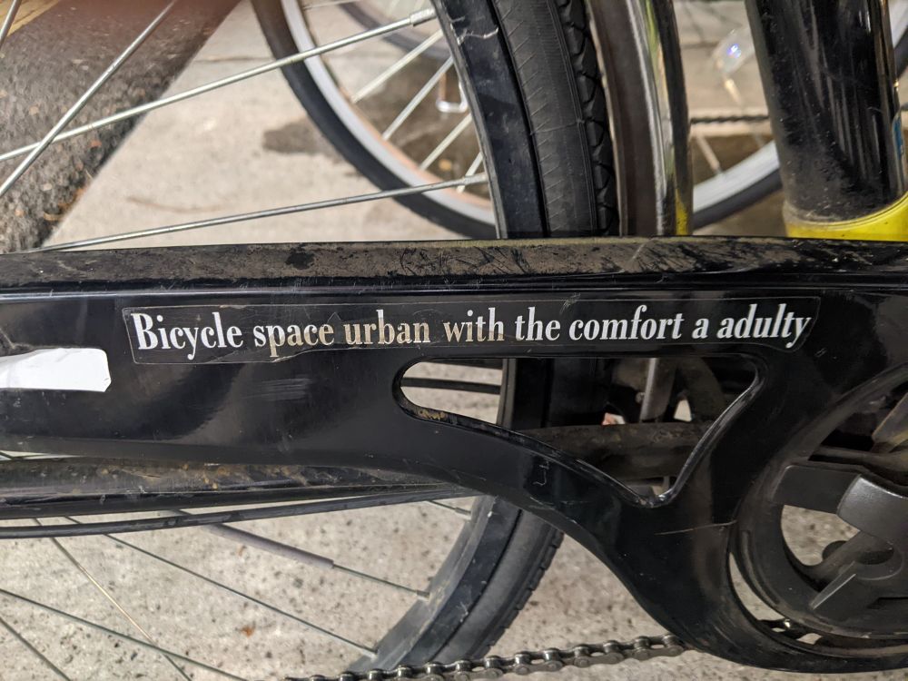 Black bicycle chain guard reading "Bicycle space urban with the comfort a adulty" in white letters