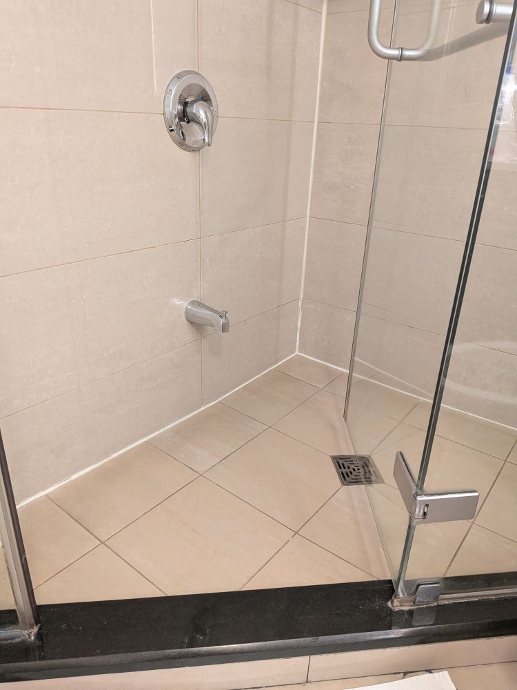 A bath spigot in a stand-up shower, with a door that opens into the very corner of the shower making it difficult to get in and out
