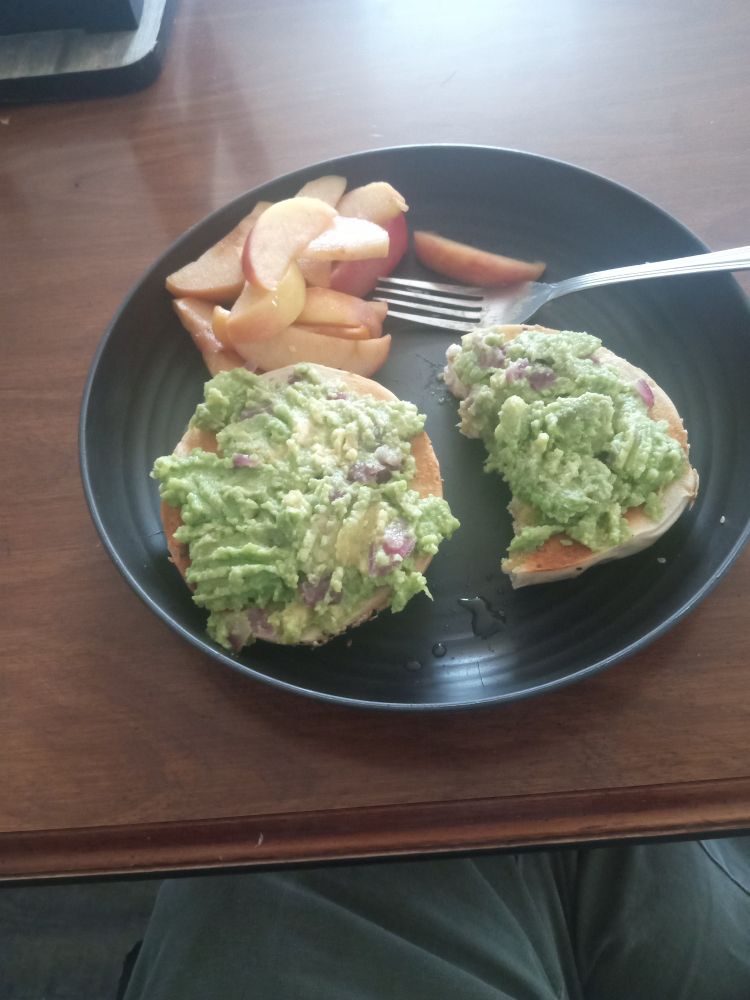 Homemade avocado spread on toasted everything bagel with sliced apples