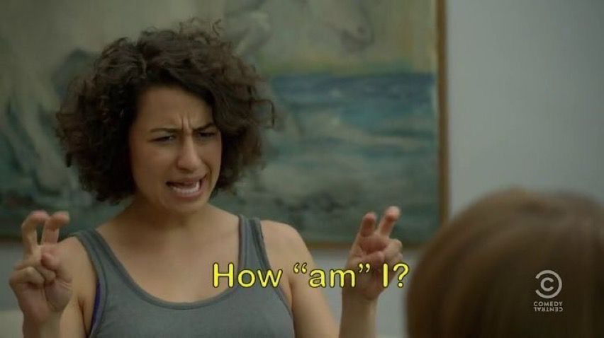 Ilana Glazer in Broad City, she’s doing air quotes and the text says “How ‘am’ I?”