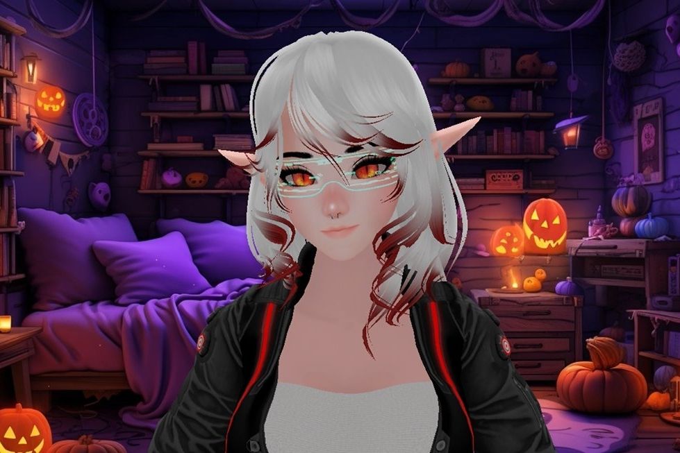 Female vtuber with white hair with red tips. She has elf ears and red eyes. She is wearing blue cyber glasses with a white shirt and a black cyber jacket with a red RGB strip down the front on either side. She is backed by a Halloween background with a bed, books, and jack-o'-lanterns.