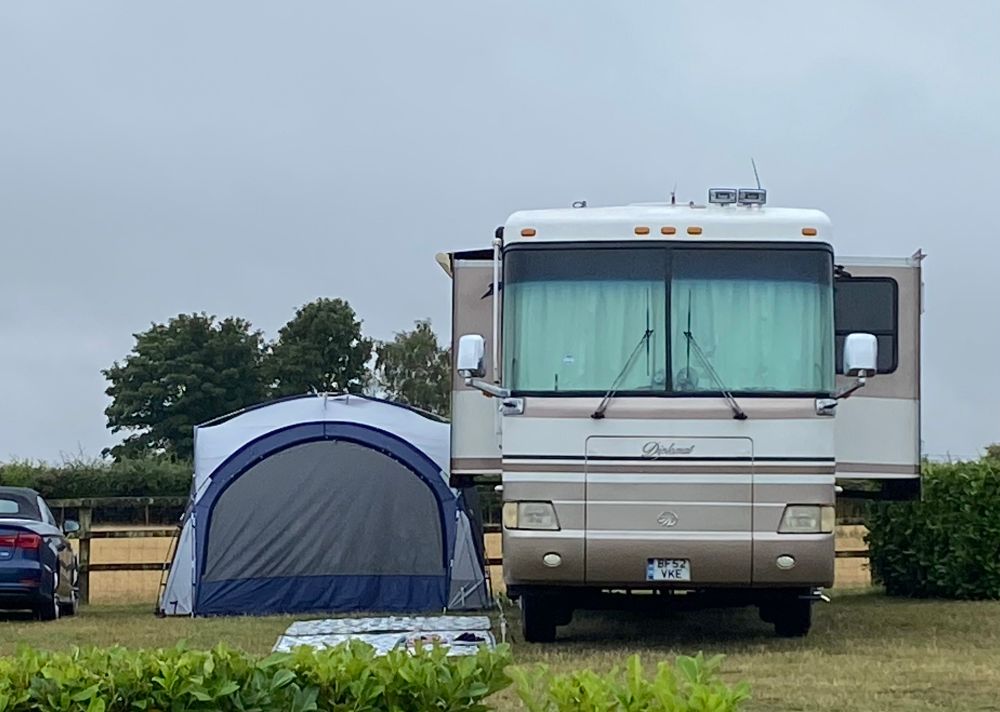 Massive camper van beside 4-person tent