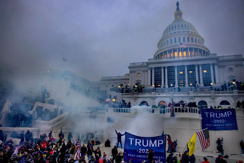 Pro-Trump supporters storm the U.S. Capitol on January 6, 2021, in an attempt to overturn the 2020 presidential election results. Amid clouds of tear gas and the chaos of the scene, rioters clash with law enforcement as they scale barriers and occupy the Capitol steps, leading to an unprecedented breach of the seat of American democracy.