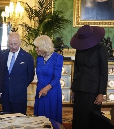A photo of King Charles, Queen Camilla and - most likely - a decoy Melania Trump made up of a few wooden planks, shoes and a purple hat.