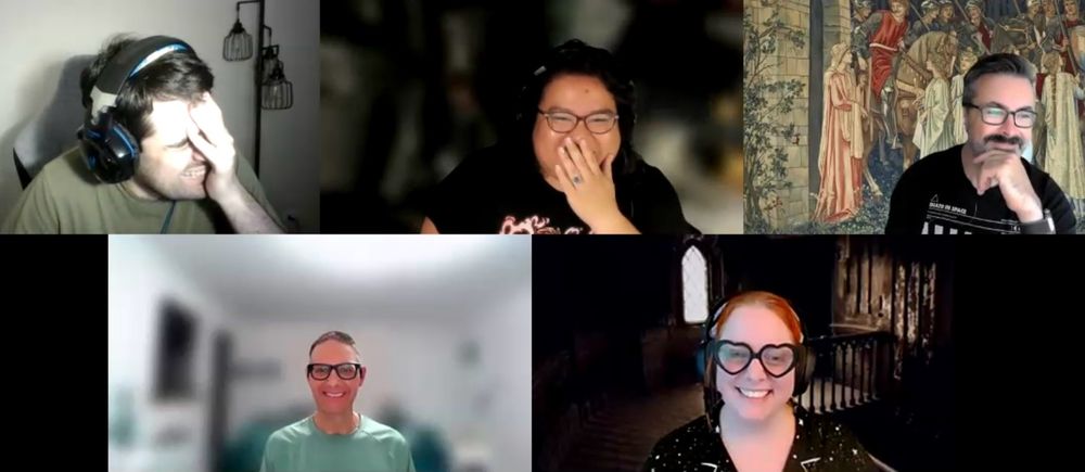 Everyone in their own Zoom window - clockwise from top left: Jeremy is laughing into his hand, away from the camera; Mads is hiding her mouth with her hand, giggling, eyes crinkling; Rob looking to the right away from the camera, a smirk on his face; Amanda is smiling directly into the camera; Mark is also smiling directly into the camera but further back in his frame so looking smaller compared to his background