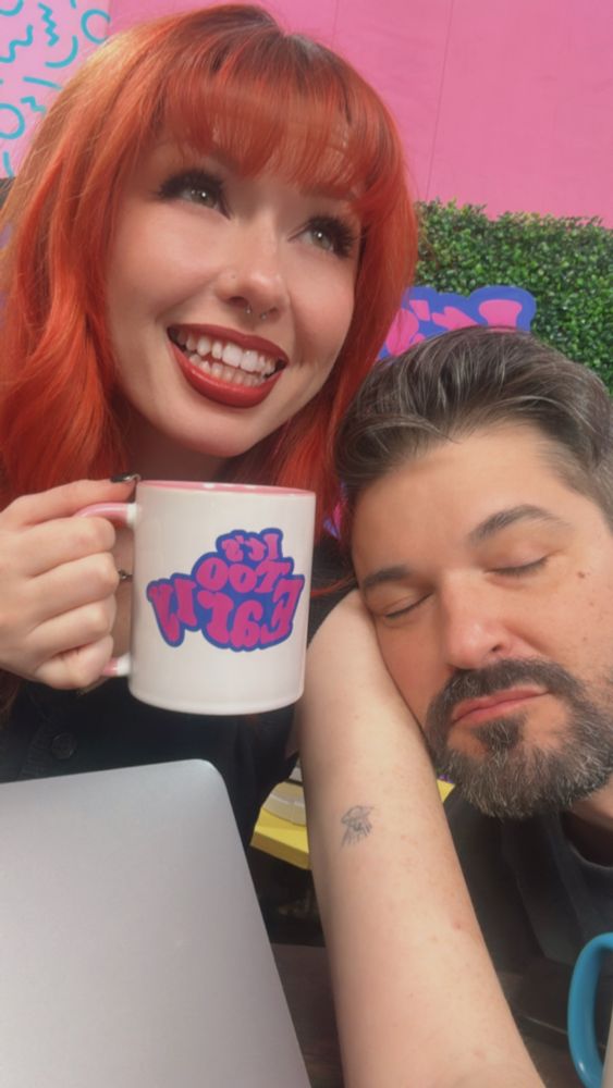 Saige smiles holding an "it's too early" mug as Anthony falls asleep on her shoulder 