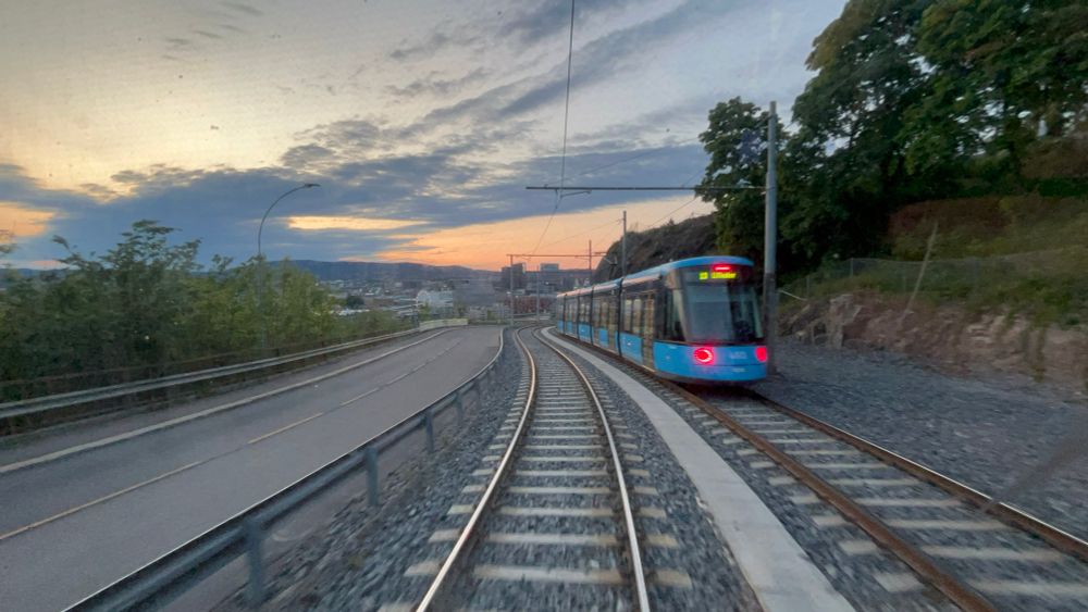 The view at sunset up a strong grade of a new tram passing the rear of the old tram.
