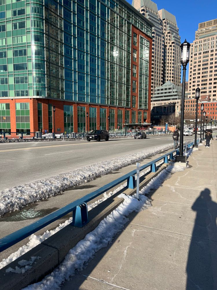 A strip of approximately 3 inches of hardened, iced-over snow forming a protected barrier for the adjacent (plowed!) bike lane on the Seaport Blvd bridge in Boston.