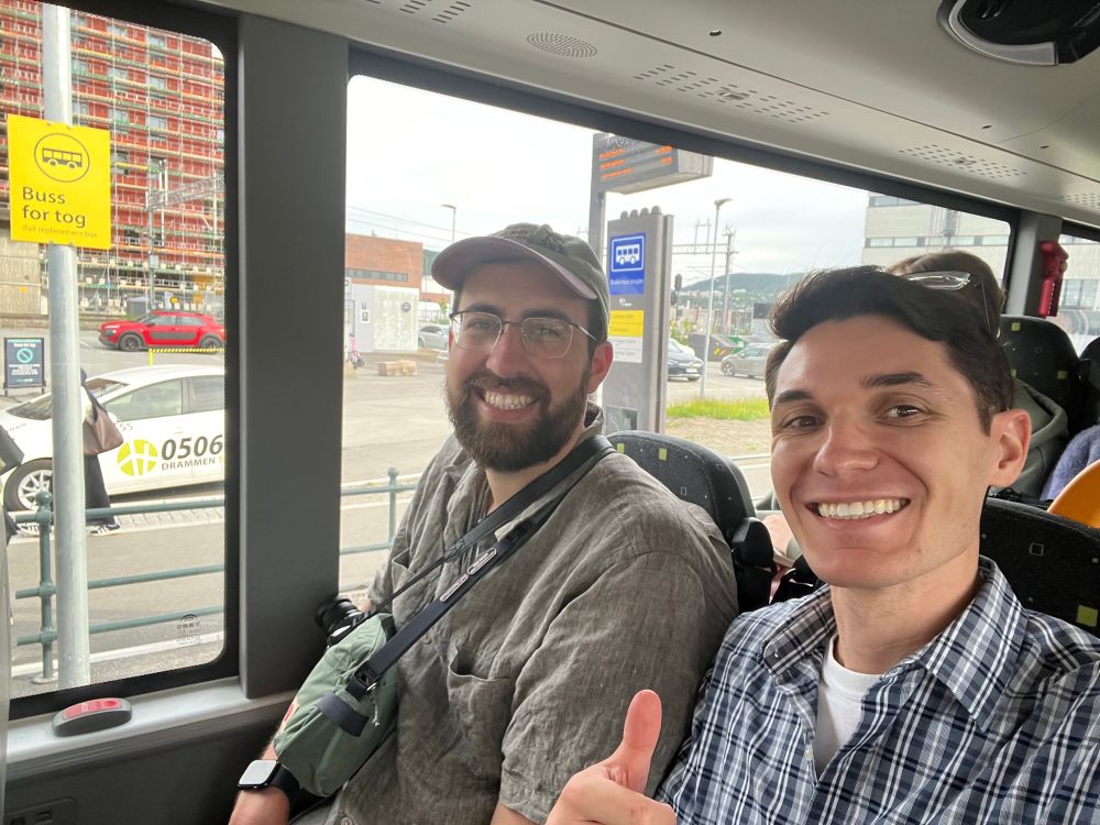 A work friend and me on the Buss for tog, in front of a sign of for the Buss for tog stop.