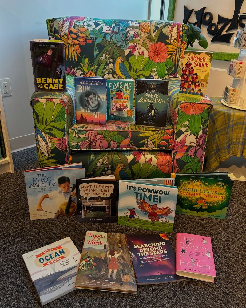 Selections of kids books from a summer reading list arranged around a cozy, floral fabric chair