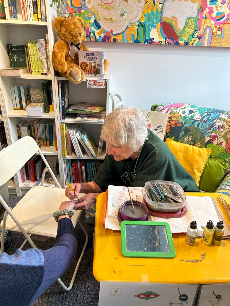 Susan’s face painting station, working on an image on someone’s hand.