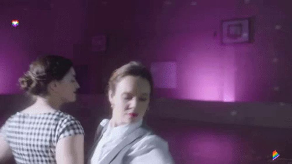 two women are dancing in a purple room .