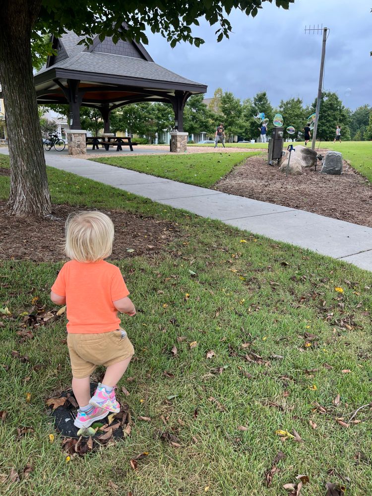 A tiny person eagerly watching huge bubbles 