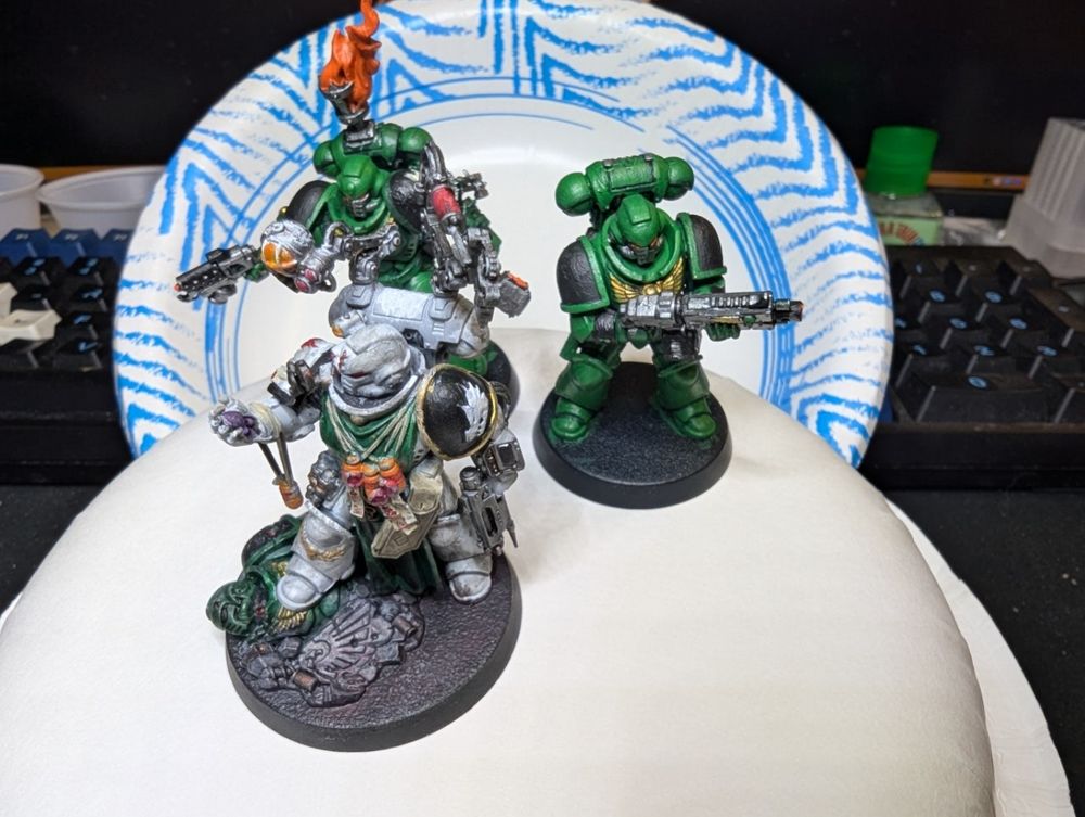 3 Warhammer 40,000 miniatures of the Space Marine faction painted as Salamanders. 