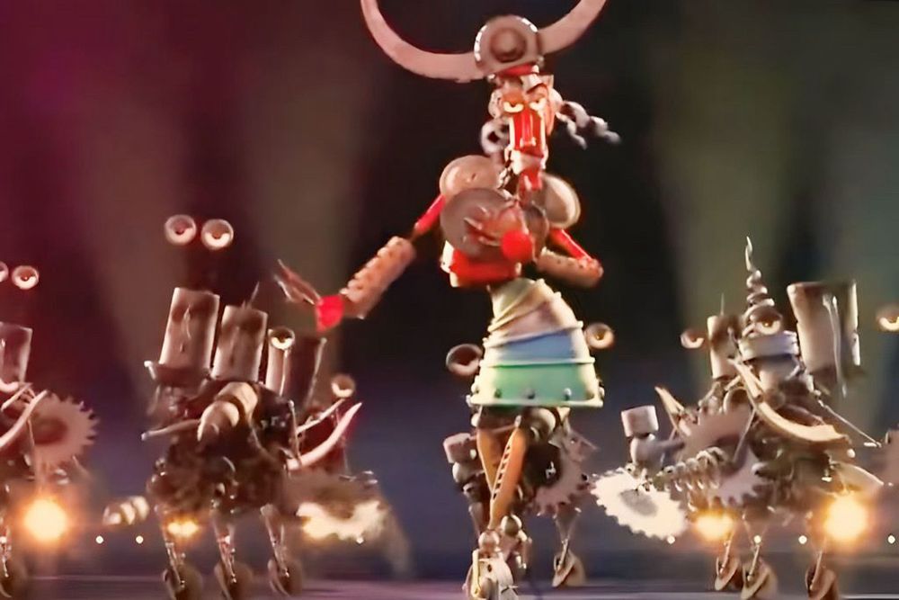 A screenshot from Robots, the movie. A red robot in a metal skirt and Viking-style attire dances in front of background dancing robots with sawblade hands. 