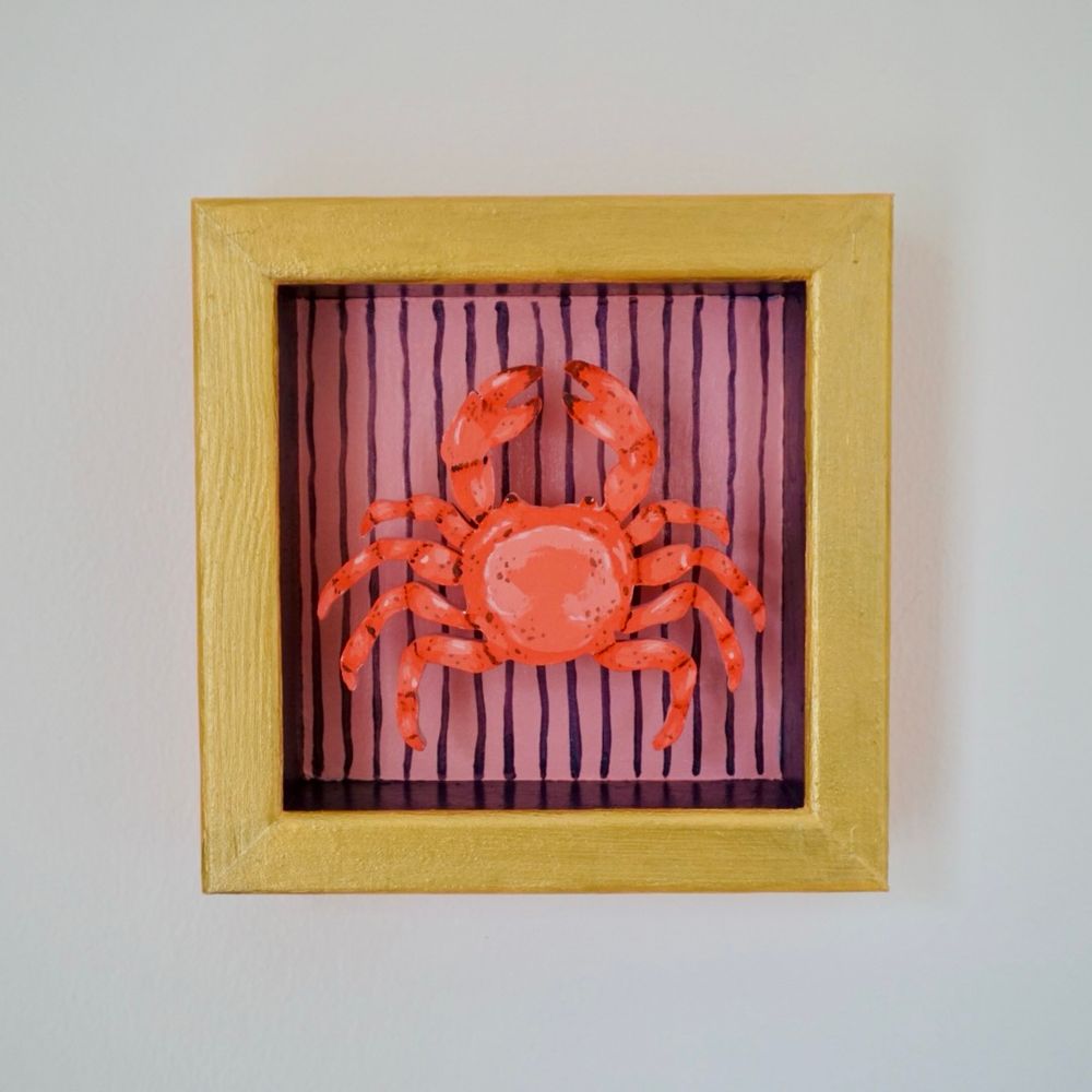 Painted crab woodcut in a painted pink wooden frame with purple stripes and gold outline