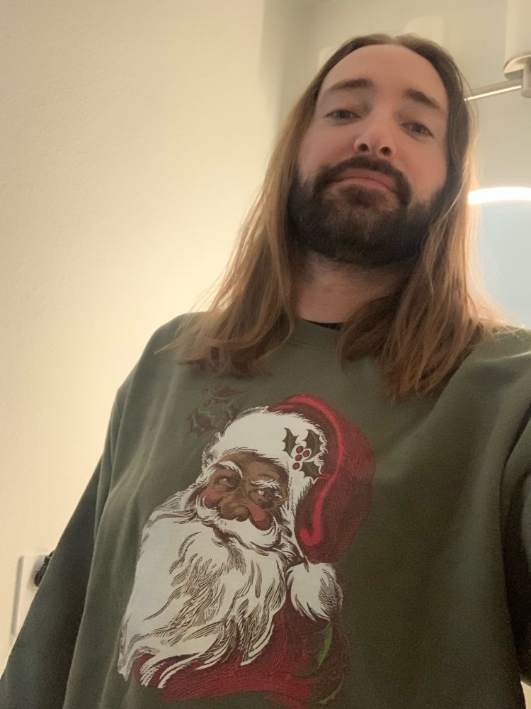 Selfie of me, white Jesus looking motherfucker, wearing a sweatshirt with Black Santa on it 