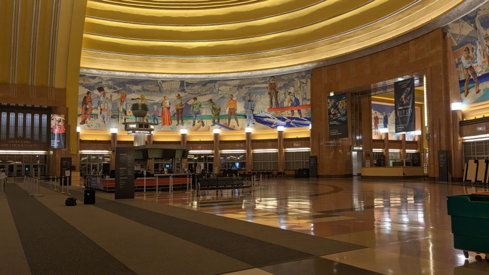 Inside the terminal is a large rotunda with a tall mural around the back and signs saying "to trains" which were also present in James Gunn's movie