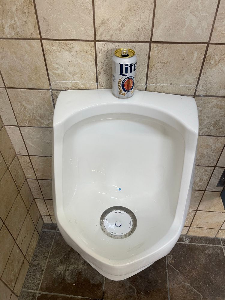 Miller lite can on a urinal. 