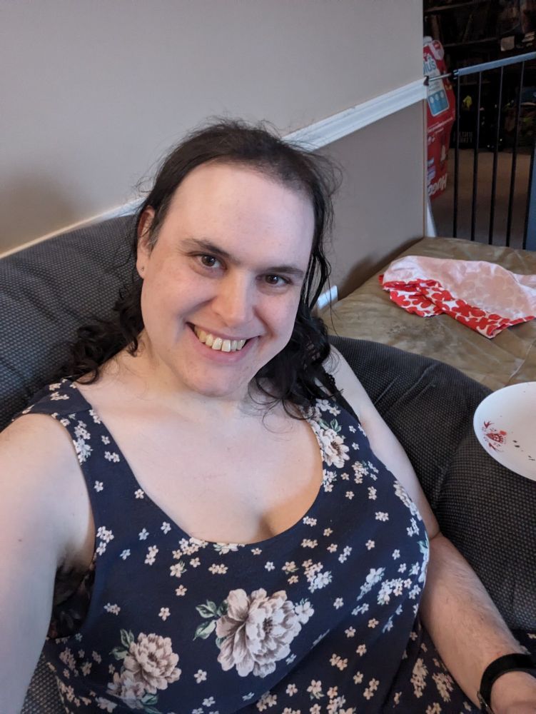 Me in a blue floral sleeveless dress smiling at the camera