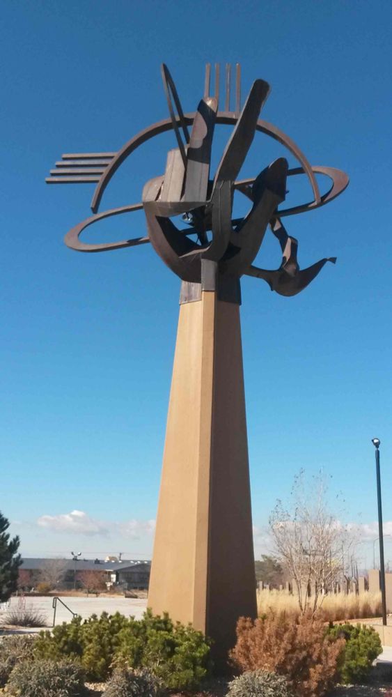 Metal sculpture atop a concrete column. Looks like a hand grasping a graphic representation of a cloud.