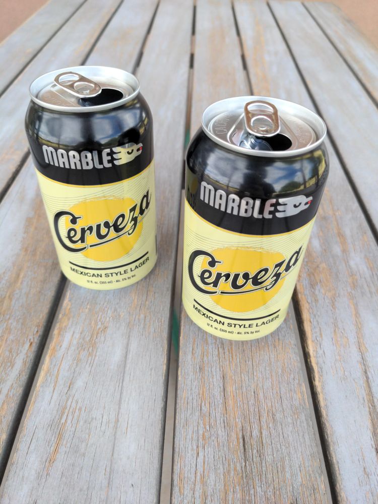 Two opened (and empty) beer cans on a table. Cerveza Mexican style lager from Marble Brewery.