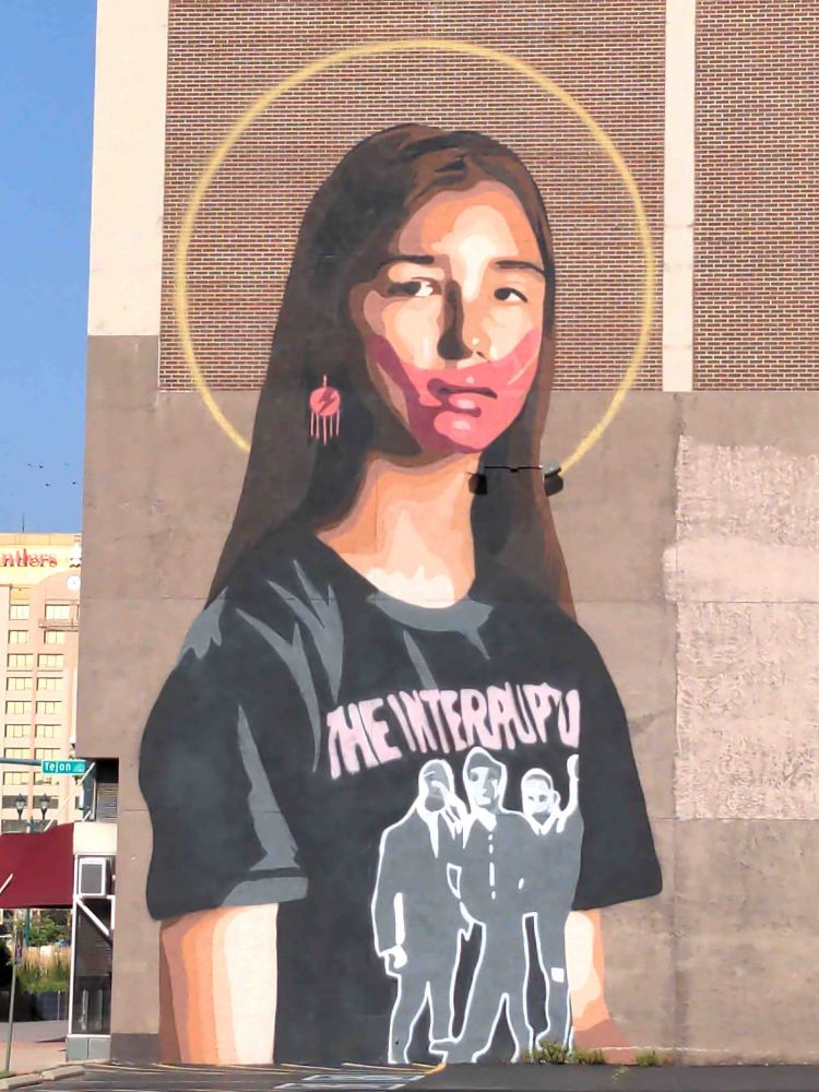 Mural on side of building is a giant portrait of a young person.