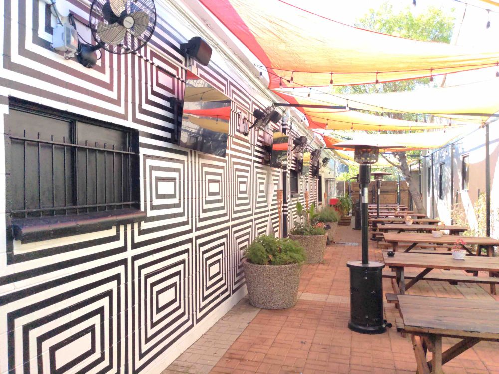 Wall adjacent to beer garden is painted with black and white graphic as if a maze or square shaped test pattern.